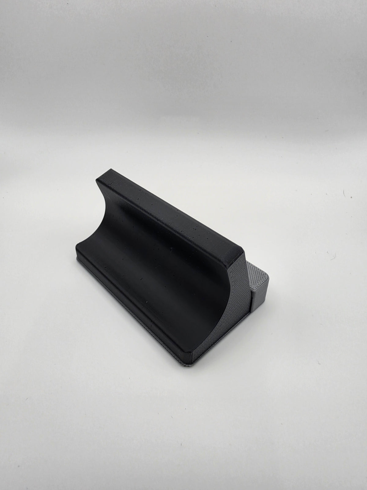 The rear of a black and gray 3D-printed charging stand, photographed on a neutral light gray background.