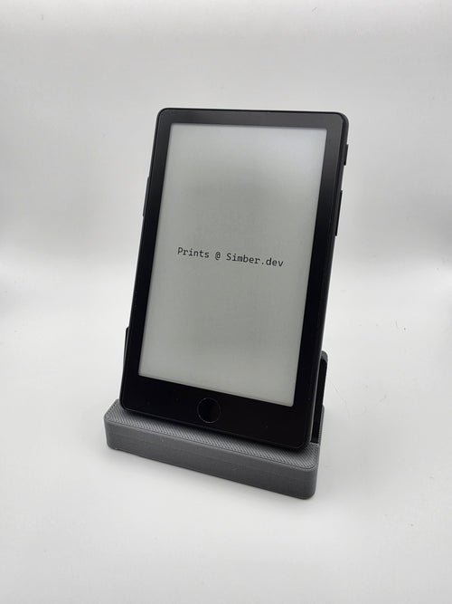 black charging stand with a rectangular charging port slot, shown on a plain white studio background, with an E-book device resting on it.