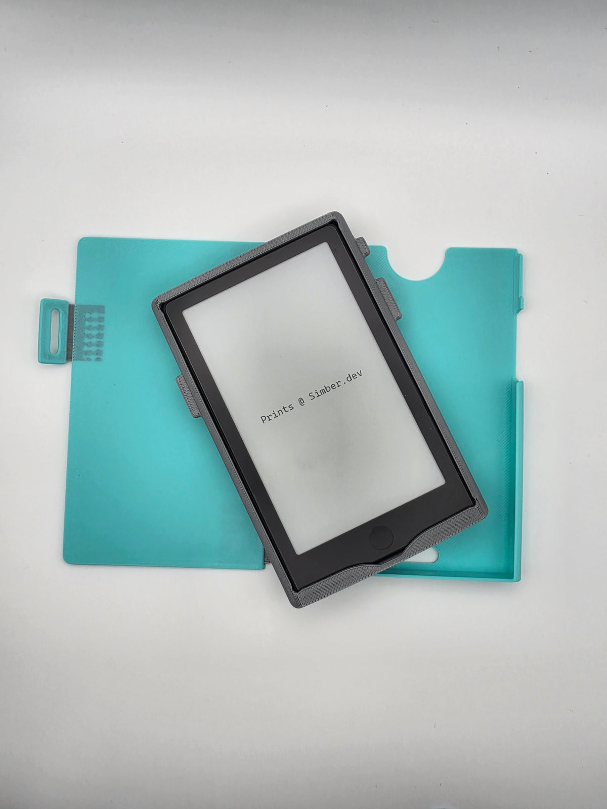 A black e-ink e-reader device with a , resting diagonally on a light blue folio protective case against a light gray background.